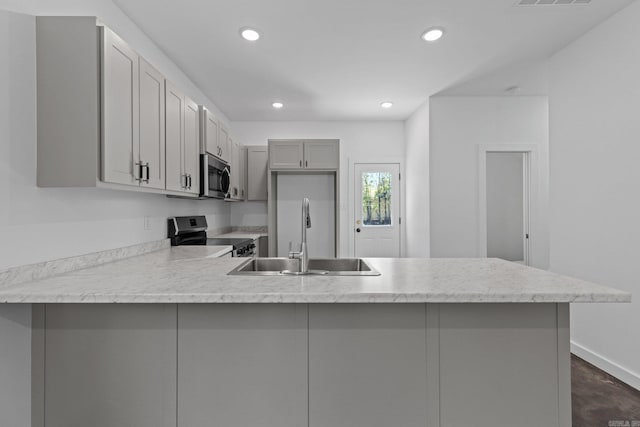 kitchen featuring kitchen peninsula, stainless steel appliances, gray cabinets, and sink