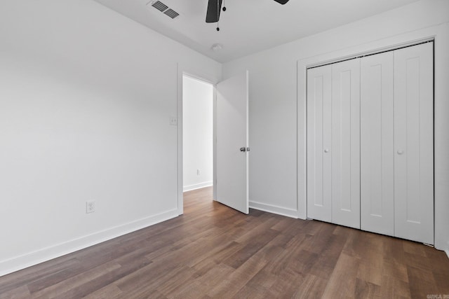 unfurnished bedroom with dark hardwood / wood-style flooring, a closet, and ceiling fan