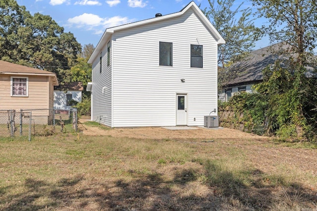 rear view of property featuring a lawn and central air condition unit