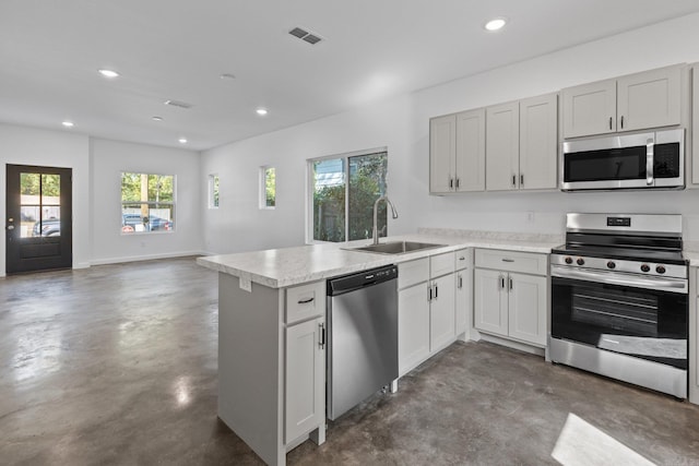 kitchen with stainless steel appliances, white cabinetry, sink, and kitchen peninsula