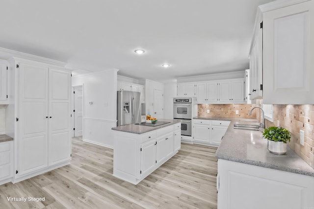 kitchen with white cabinets, sink, light hardwood / wood-style floors, a kitchen island, and stainless steel appliances