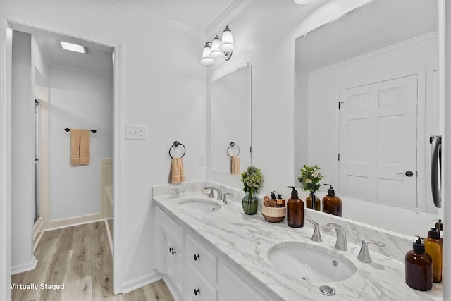 bathroom featuring hardwood / wood-style flooring, vanity, a shower with shower door, and ornamental molding