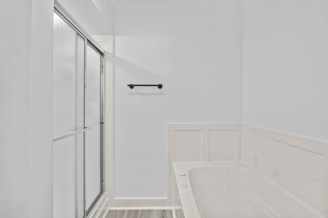 bathroom with plus walk in shower, ornamental molding, and hardwood / wood-style flooring