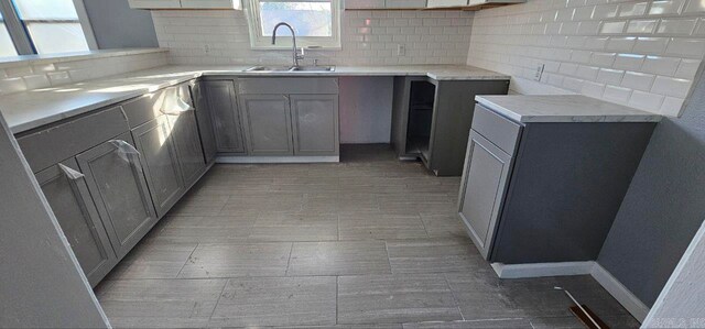 kitchen with decorative backsplash, gray cabinetry, and sink