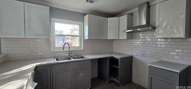 kitchen featuring sink, wall chimney exhaust hood, decorative backsplash, light stone countertops, and ornamental molding