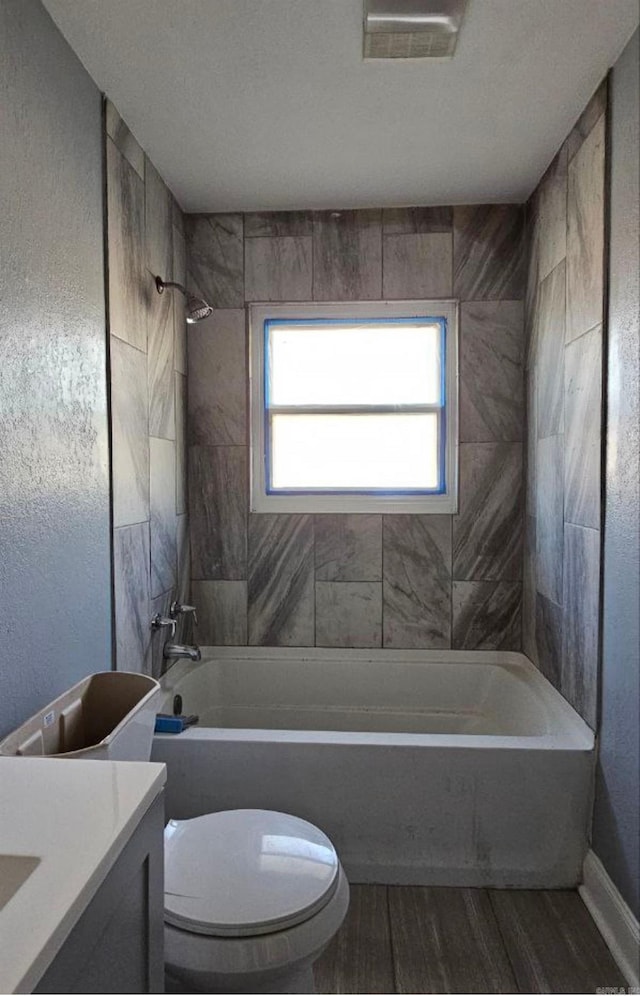 full bathroom with vanity, hardwood / wood-style floors, tiled shower / bath combo, and toilet