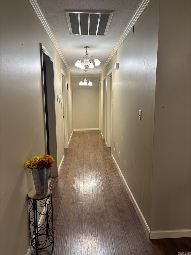 hall with dark hardwood / wood-style flooring, an inviting chandelier, and ornamental molding