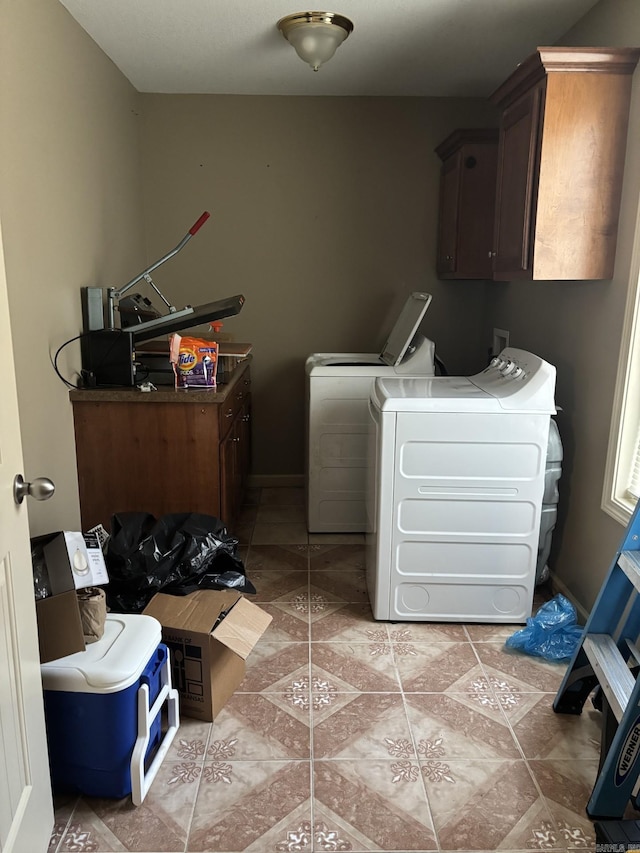 clothes washing area with washer and dryer, cabinets, and light tile patterned floors