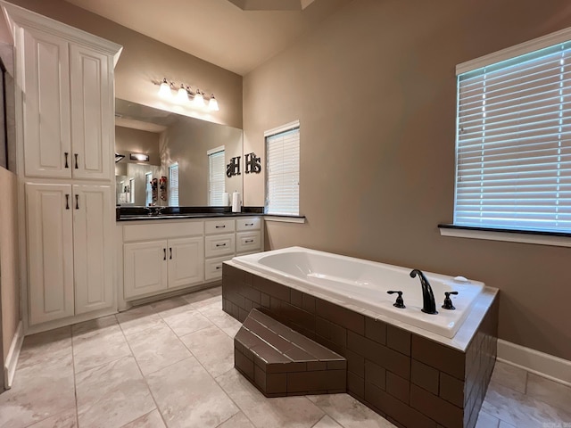 bathroom with tile patterned floors, vanity, and a relaxing tiled tub