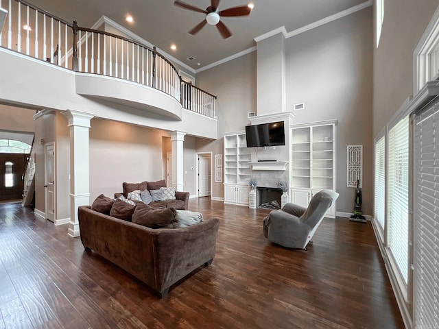 living room featuring dark hardwood / wood-style flooring, a towering ceiling, crown molding, and a premium fireplace