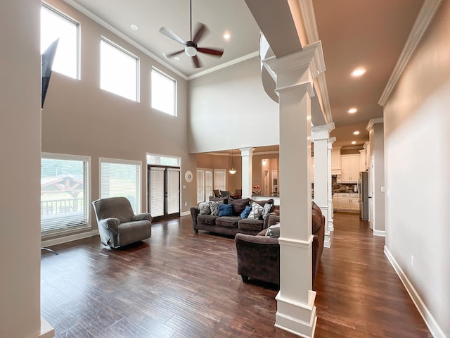 living room featuring dark hardwood / wood-style floors, ceiling fan, ornate columns, and a wealth of natural light