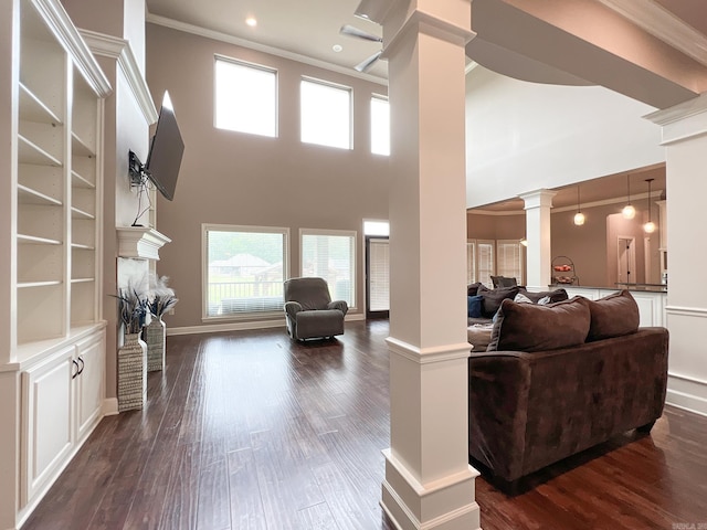 living room featuring decorative columns, crown molding, dark hardwood / wood-style flooring, and a towering ceiling