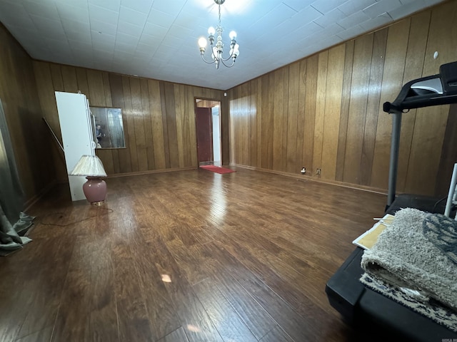 interior space featuring wooden walls, a chandelier, and dark hardwood / wood-style floors