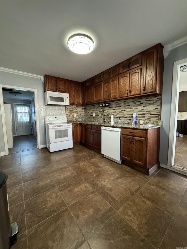 kitchen featuring decorative backsplash, light stone counters, white appliances, crown molding, and sink