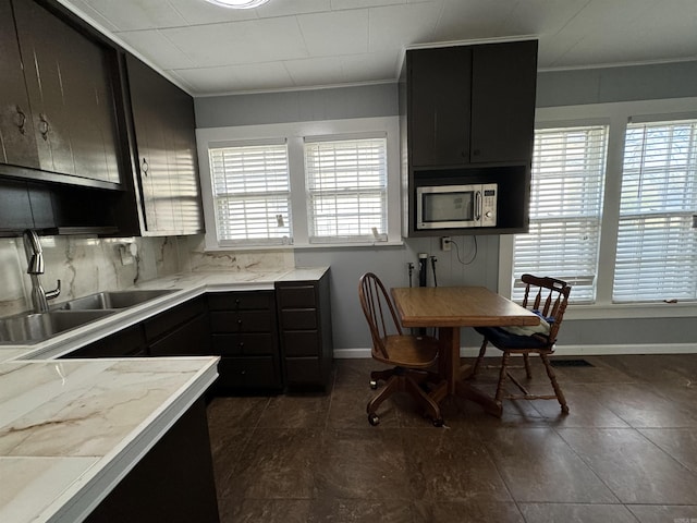 kitchen featuring backsplash, crown molding, a healthy amount of sunlight, and sink