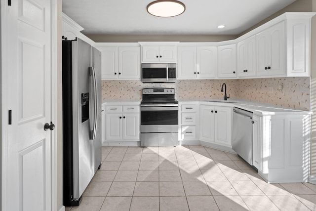 kitchen with light tile patterned flooring, appliances with stainless steel finishes, white cabinets, and sink