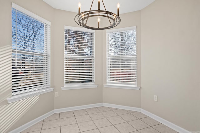 tiled spare room featuring a notable chandelier