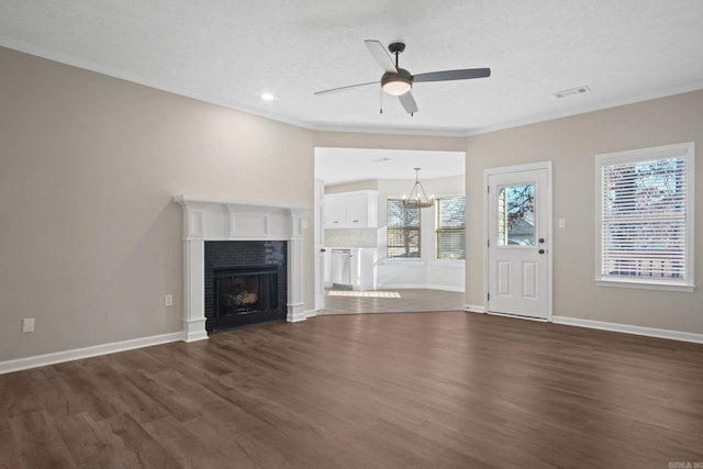 unfurnished living room with plenty of natural light, dark hardwood / wood-style floors, ceiling fan with notable chandelier, and a brick fireplace