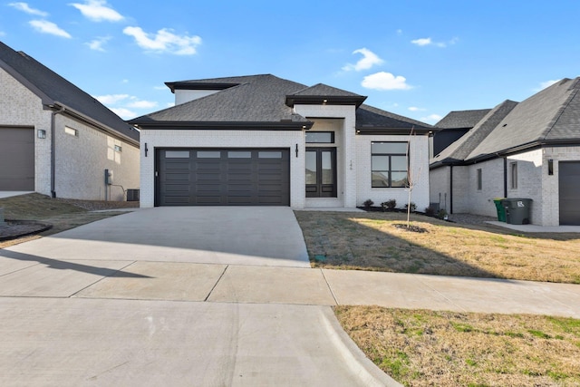 prairie-style home with french doors, a garage, and a front lawn