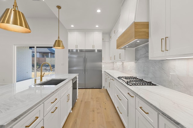 kitchen with white cabinetry, appliances with stainless steel finishes, light stone counters, and a sink