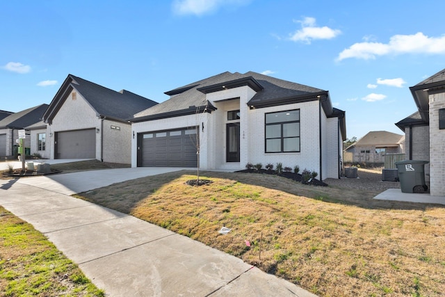 view of front of house with an attached garage, driveway, a front lawn, and brick siding