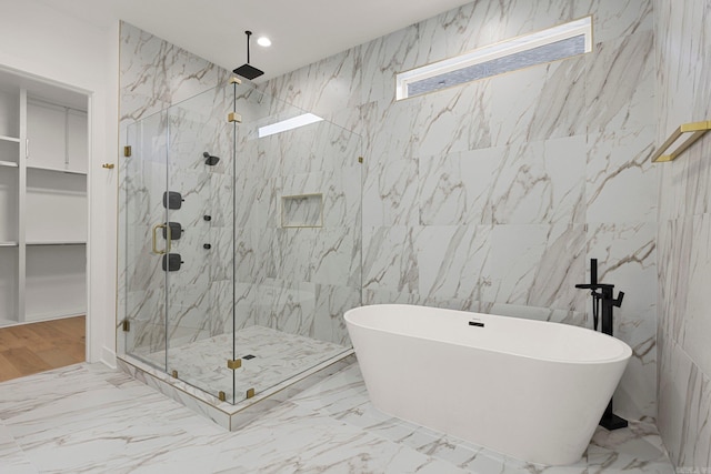 bathroom featuring a walk in closet, marble finish floor, a marble finish shower, recessed lighting, and a freestanding bath