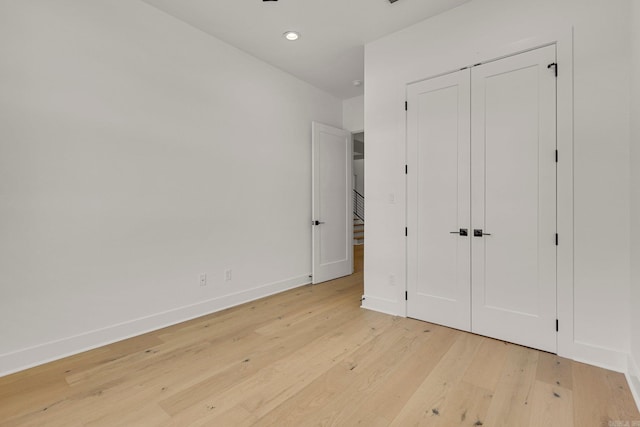 unfurnished bedroom featuring light wood-type flooring, baseboards, a closet, and recessed lighting