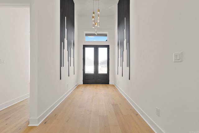 foyer entrance with light wood-style floors, baseboards, and french doors