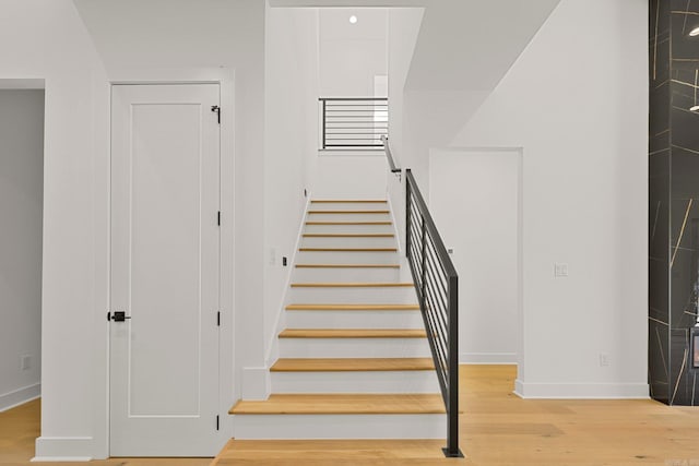 staircase featuring wood finished floors and baseboards