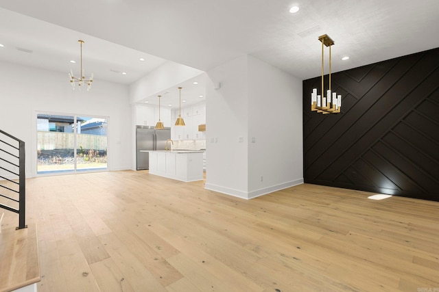 unfurnished living room featuring light wood-type flooring and a notable chandelier