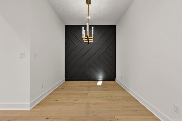 unfurnished dining area with wood walls, light wood-style flooring, and baseboards