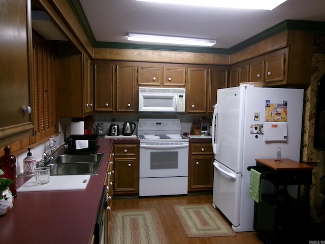 kitchen with wood-type flooring, sink, and white appliances