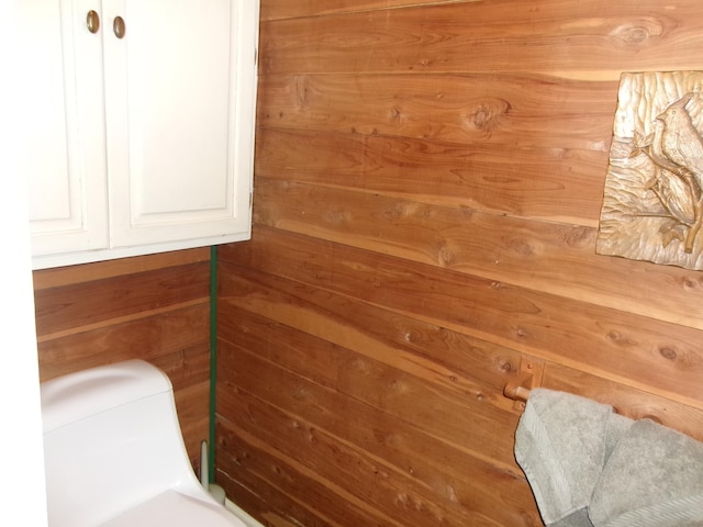 bathroom featuring toilet and wood walls