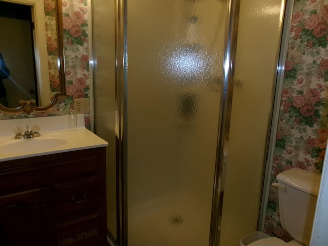 bathroom featuring vanity, a shower with door, and toilet