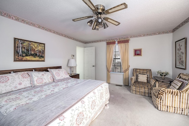 carpeted bedroom with ceiling fan and a textured ceiling