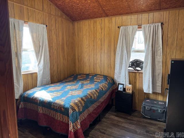 bedroom featuring wooden walls, dark hardwood / wood-style flooring, wood ceiling, and vaulted ceiling