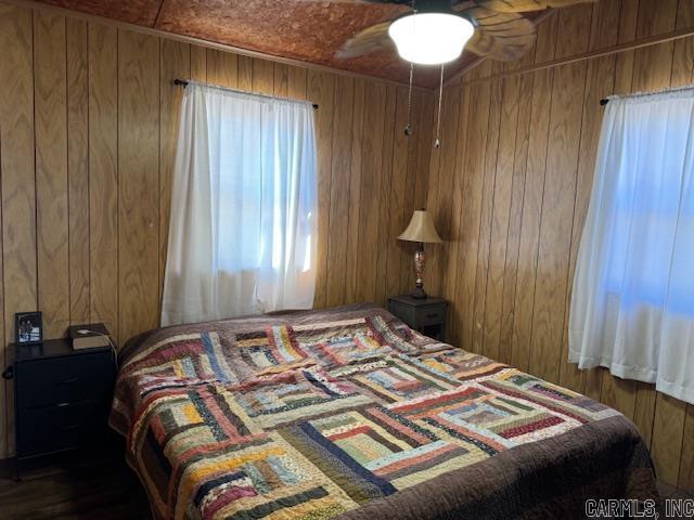 bedroom featuring wood walls and ceiling fan