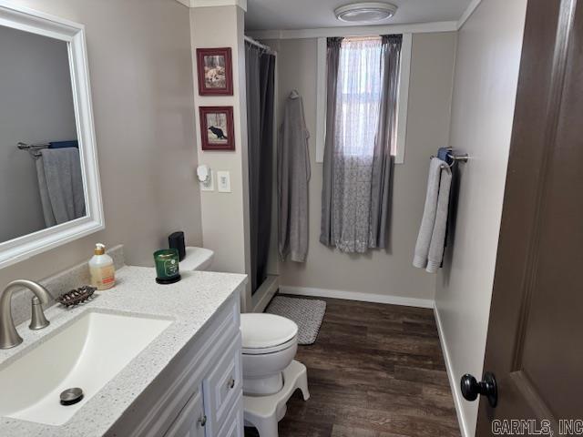 bathroom featuring a shower with shower curtain, ornamental molding, vanity, wood-type flooring, and toilet