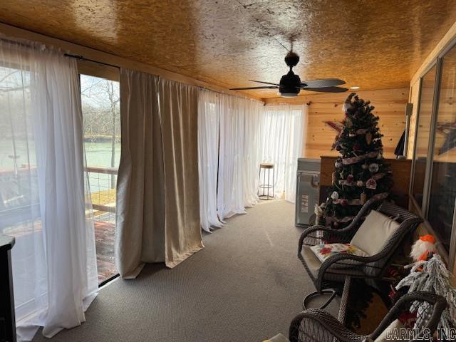 interior space featuring carpet flooring, ceiling fan, and wooden walls