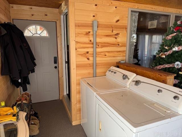 clothes washing area featuring separate washer and dryer, wood walls, and rustic walls