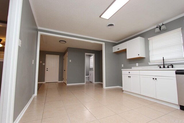 kitchen featuring light tile patterned floors, white cabinetry, ornamental molding, and sink