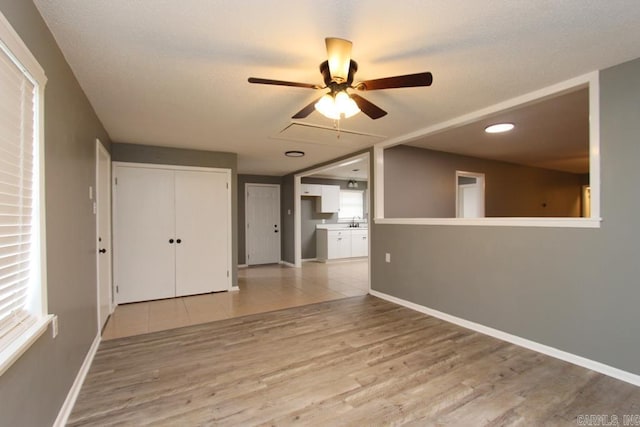 unfurnished room with light wood-type flooring, ceiling fan, a healthy amount of sunlight, and sink