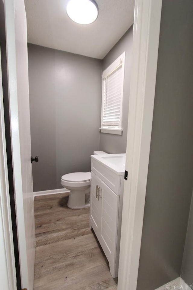 bathroom with hardwood / wood-style floors, vanity, and toilet