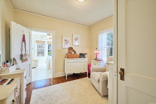 interior space with a textured ceiling, ceiling fan, dark hardwood / wood-style floors, and ornamental molding