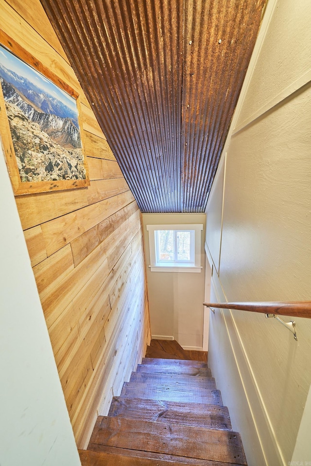 stairway featuring wood walls, wooden ceiling, and vaulted ceiling