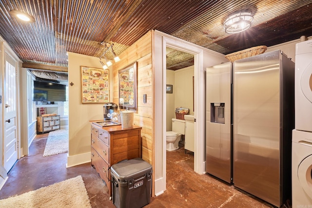 bathroom featuring concrete flooring, stacked washer and dryer, toilet, and wood ceiling