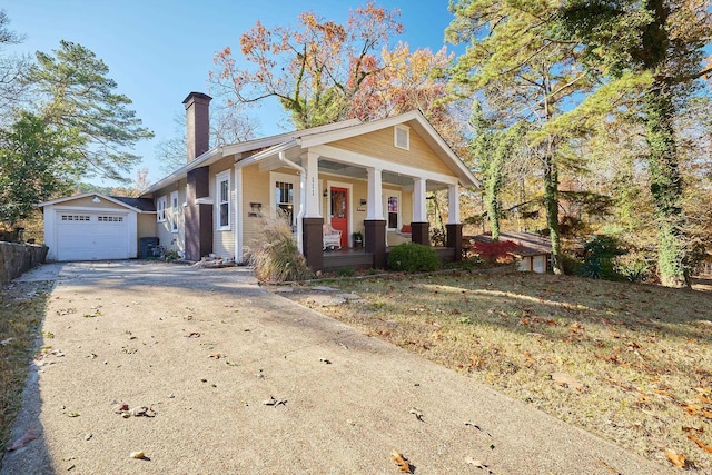 view of front of house featuring an outbuilding, a porch, a garage, and a front lawn