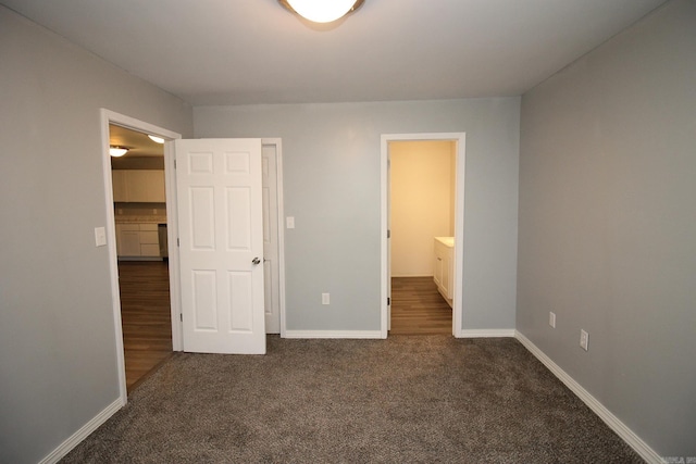 unfurnished bedroom featuring dark colored carpet and ensuite bathroom