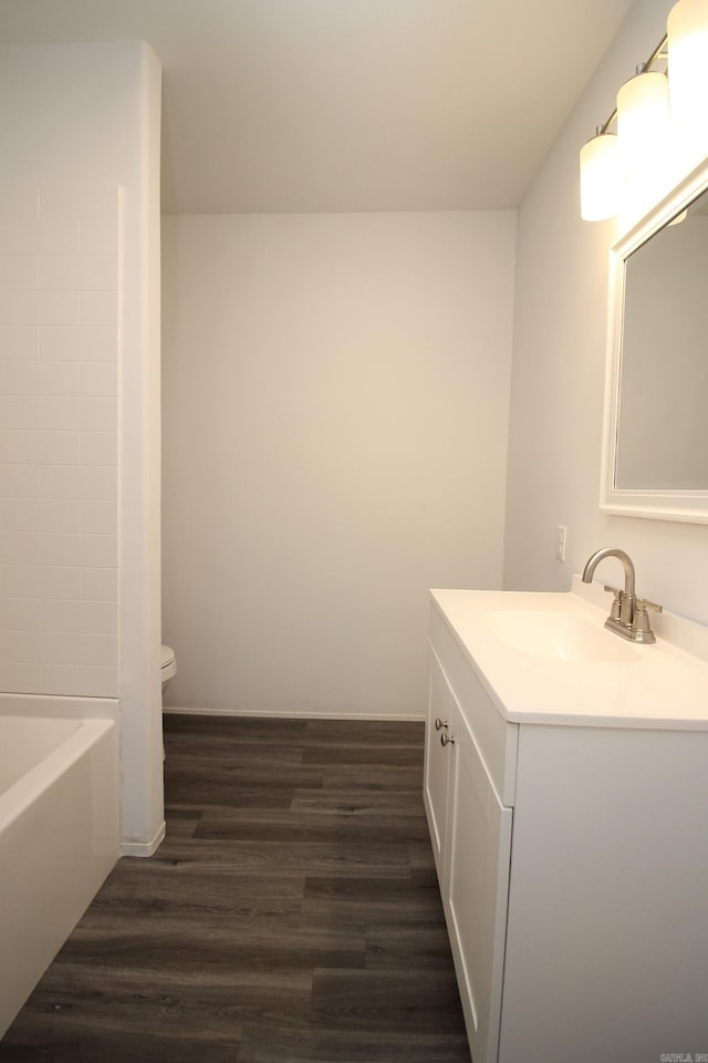 bathroom with a bathing tub, hardwood / wood-style flooring, vanity, and toilet