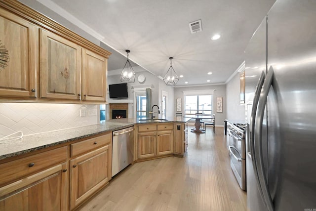 kitchen with sink, hanging light fixtures, kitchen peninsula, decorative backsplash, and appliances with stainless steel finishes